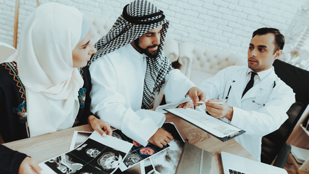 Muslim Family Visiting Doctor at Medical Clinic. Arabic Man Signs Contract. Consultation at Clinic....