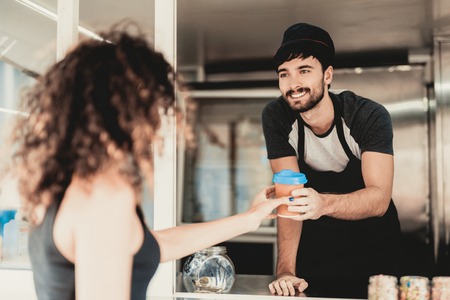 Girl in Black Dress Buying Snacks in Food Truck. Promenade in Town. Summer Day. Girl in Black Dress. Street Food Concept. Cup of Coffee. Buying Food Outdoor. Food in Town. Selling Snacks.の写真素材