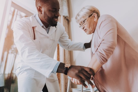Woman Tell about her Condition. Woman Try to Stand Up. Doctor Helps Woman Get Up. Patient Feel Sick. Smiling Doctor. Doctor Examines Elderly Patient. Nursing Home. Doctor Interviews Woman.の写真素材
