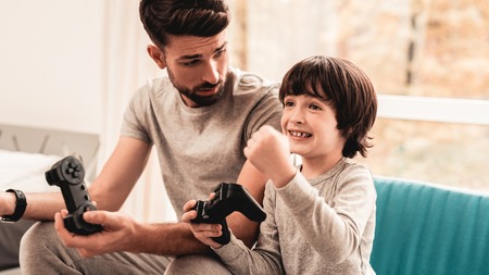 Father and Son Sitting and Playing on Console. Sitting Boy. Young Father. Playing on Console....