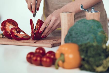 Female Hands Slicing Bell Pepper on Wooden Board.の写真素材