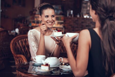 Happy Women Have Tea and Cake in Restaurant.の写真素材