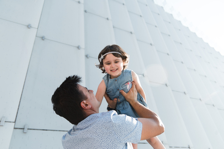 Father's day concept. Father throwing his little daughter in the air. Happy and joyfull child playing with his father.の写真素材