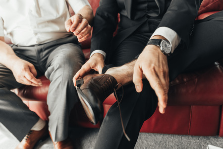 Close-up of fashion image of man's luxury watch on wrist. Businessman in black suit with watch on hand. Fastening a wristwatch. Body detail of a business man. Man's hand in a white shirtの写真素材