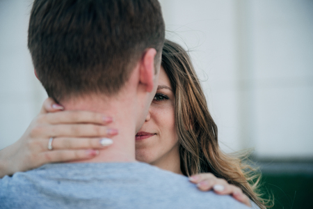 Young couple kissing. Girl hugging a man's neck. Young man standing back and girl is hugging his neckの写真素材