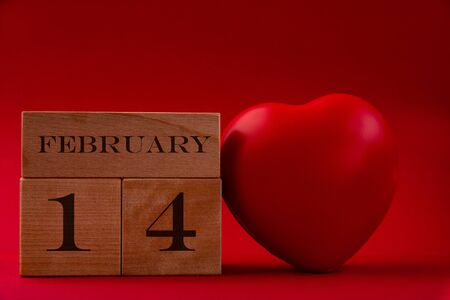 Wooden cubes with the inscription February 14 and a big heart on a red background
