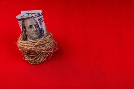 Dollar bill wrapped in linen thread on a red backgroundの写真素材