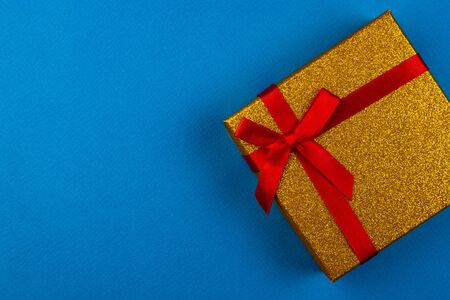 Gift box with a red bow on a blue backgroundの写真素材