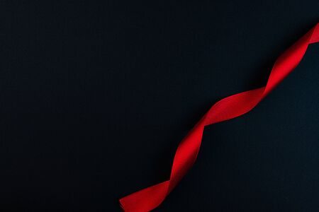 A spiral of red satin ribbon, on a black background.の写真素材