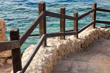 Stone stairs and wooden fence lead to the seaの写真素材