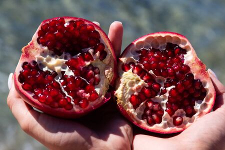 Girl shares a ripe pomegranate. Juice of this fruit is useful to healthの写真素材
