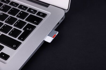 SD flash drive inserted into laptop on black background