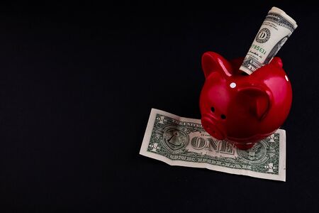 Dollars banknotes money into Piggy Bank on a black background.,money saving financial concept.の写真素材