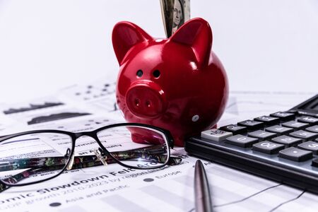 Piggy bank with cash and calculator on business documents background