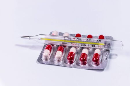 Thermometer with a blister of pharmacy pills.