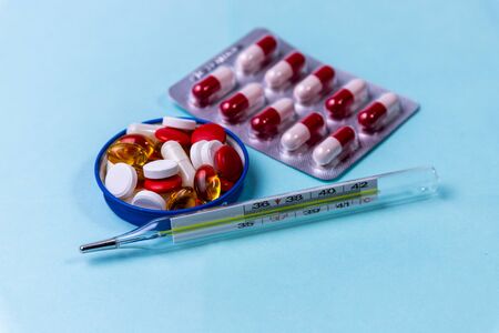 Pills and thermometer on a blue backgroundの写真素材