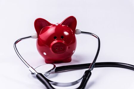 Piggy bank with stethoscope isolated on white concept for financial checkup or saving for medical insurance costsの写真素材
