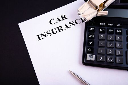 Car insurance concept with calculator on a black tableの写真素材