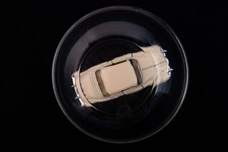 White car is protected under a glass dome on a black background