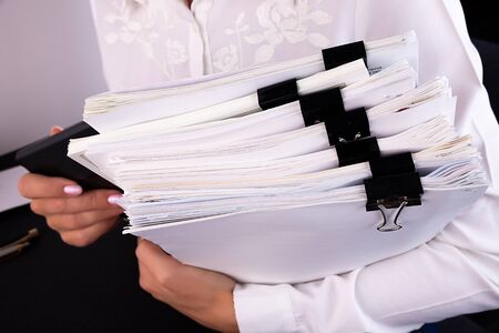 Business woman office workers holding are arranging documents of unfinished documents on office desk,Stack of business paper,document management,Businesswoman examining documentsの写真素材