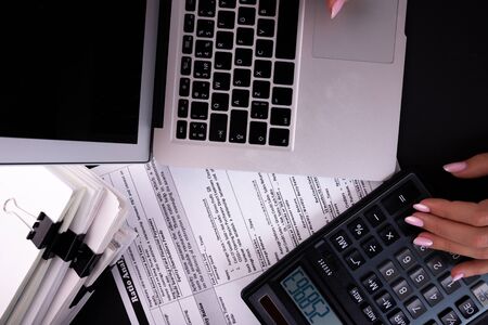 Business woman works in the office. Woman presses buttons on the keyboard and on the calculator.の写真素材