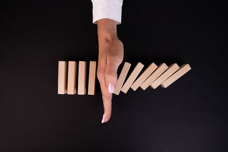 Businesswoman hand Stopping Falling wooden Blocks or Dominoes. Business, Risk Management, Solution, Insurance and strategy Conceptsの写真素材