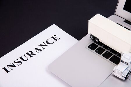 Insurance form with laptop and truck on a black backgroundの写真素材