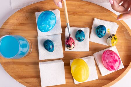 easter, holidays, tradition and people concept - close up of woman hands coloring easter eggs with...