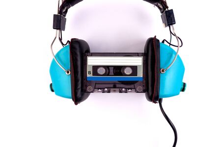 Wired headphones with audio tape on a white background. Retro style, DJ. Top view, minimalistic...