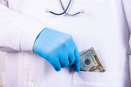 A portrait of a male doctor with money in his pocket isolated on white background