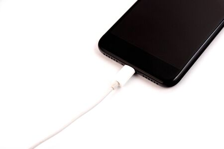 Black smartphone is charging on a white background