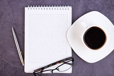 Business desk with office supplies, notebook, pen, flower, glasses on a dark background. Flat...