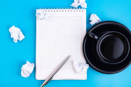 Open a blank white notebook with pen and cup of coffee and crumpled papers, on a blue table. Business conceptの写真素材