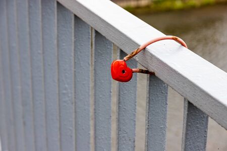 Red padlock of the heart shape on the fence of a river wharf