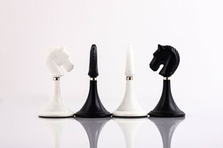 White and black chess pieces on a reflective surface. Business concept. Game, strategy, wisdom, determination.の写真素材