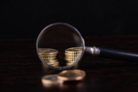 Magnifier and coins on a black backgroundの写真素材