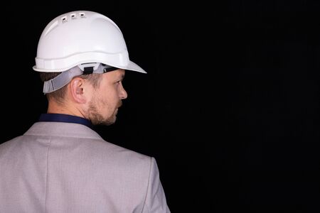 Engineer with white hard hat standing confidently isolated on black background