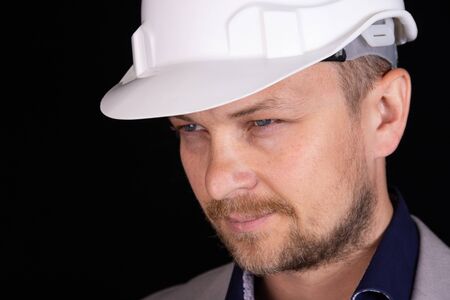Engineer, builder, businessman in a white helmet on a dark background. Portrait. The concept of...