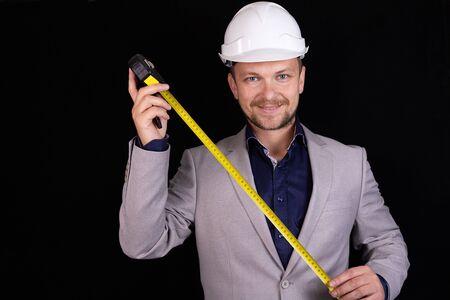 Engineer, builder, businessman in a white helmet on a dark background. Portrait. The concept of engineering, business, construction, urban life and the future.の写真素材