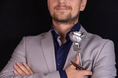 Businessman with a forged rose on a black background with a place for inscription. Business concept of strength and courage.の写真素材