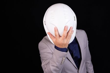Engineer, builder, businessman in a white helmet on a dark background. Portrait. The concept of engineering, business, construction, urban life and the future.の写真素材