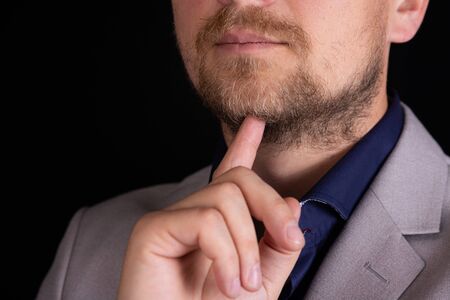 Businessman in a gray suit thinks on a black background. Business concept, idea.
