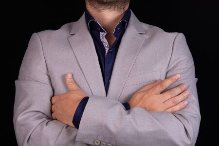 Businessman in a gray suit with folded arms on a black background. Business, finance, ideas.の写真素材