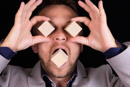 Businessman expresses emotion with his hands and face with wooden blocks. Business concept for successful growth. Information. Symbol. Sign.の写真素材