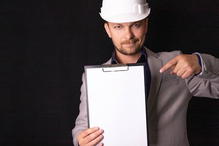 Engineer, builder, businessman in a white helmet on a dark background. Portrait. The concept of...