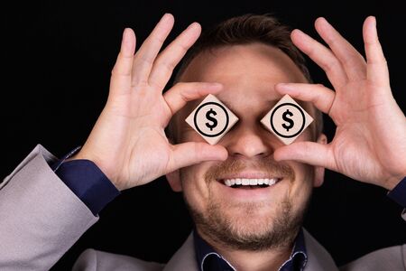 A businessman expresses emotions with his hands and face with wooden blocks and signs of US dollars....
