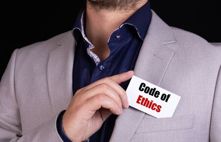Businessman putting a card with text code of ethics in the pocketの写真素材