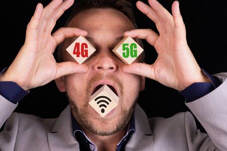 Business concept of choosing and comparing 4G and 5G communication standards. The businessman holds cubes with the words 4G nano 5G on each cube, respectively.の写真素材
