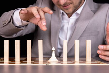 A businessman is building a pyramid of chess pieces and wooden blocks. The concept of construction, growth, development, success.の写真素材
