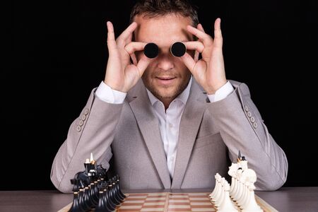A businessman expresses emotions with his hands and his face with chess pawns with humor. Business...